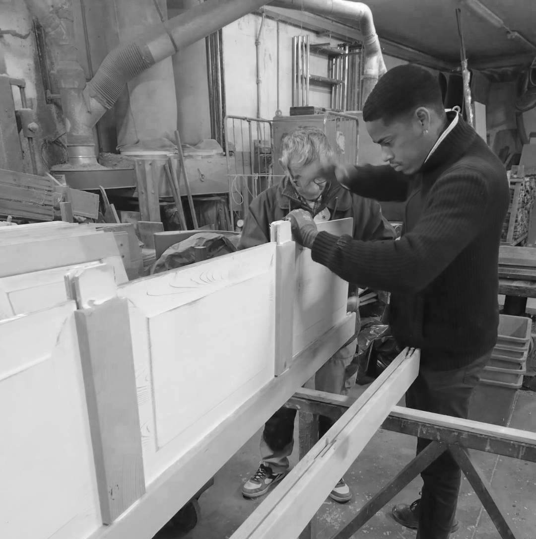 Interno del laboratorio di falegnameria artigianale ProBauen, con attrezzi tradizionali appesi alla parete e un banco da lavoro in legno. L'ambiente è ben illuminato e ordinato, suggerendo un luogo dove abilità e cura del dettaglio si uniscono nella lavorazione del legno.