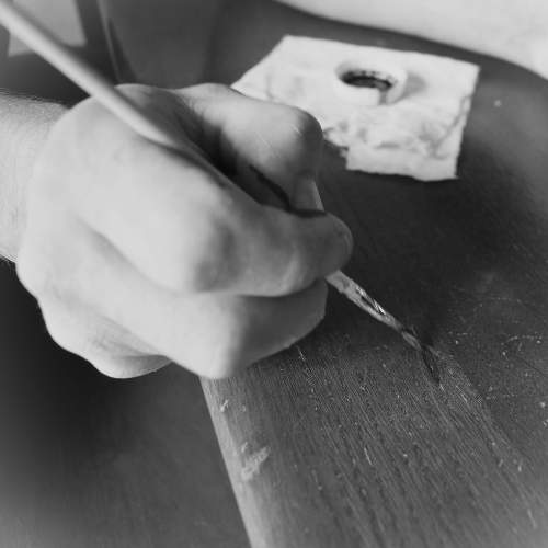 Primo piano di una mano esperta che applica con precisione un trattamento o colore su una superficie in legno, simboleggiando il restauro sostenibile e la cura artigianale di ProBauen. Questa immagine rappresenta l'attenzione meticolosa ai dettagli nel restauro di portoni, serramenti e parti in legno, utilizzando tecniche e materiali che preservano l'originalità e la durabilità. Un processo che unisce tradizione e innovazione per un risultato di alta qualità e rispettoso dell'ambiente.